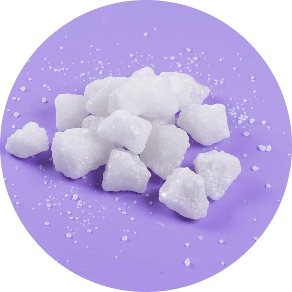 Top view of white magnesium crystal chunks showing coarse, granular texture on a purple circular background